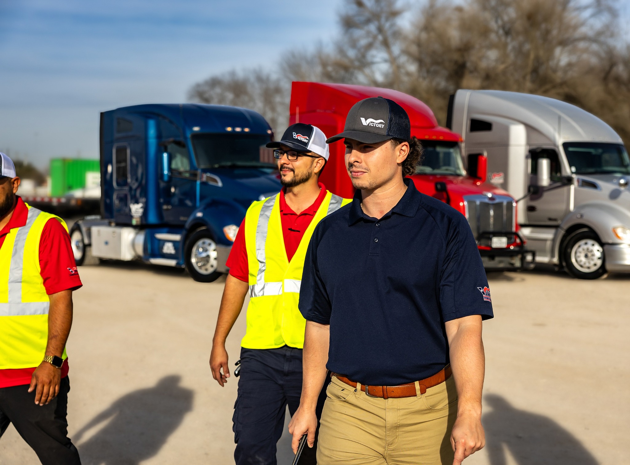 Victory team members walking together in front of the company fleet